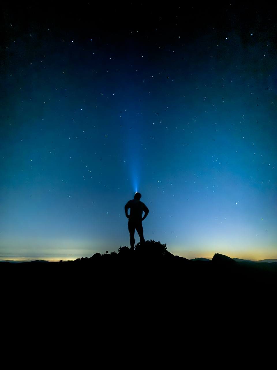Sam Blaze on a summit at altitude under a star-filled night sky.